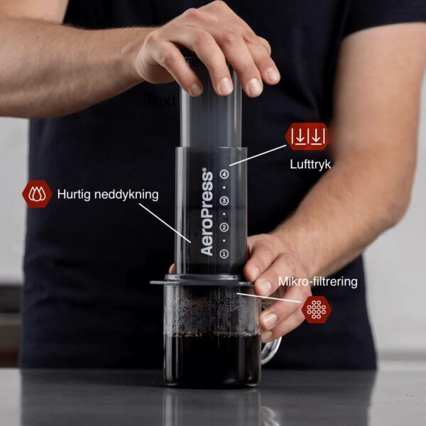 Mand brygger kaffe med AeroPress på køkkenbord.