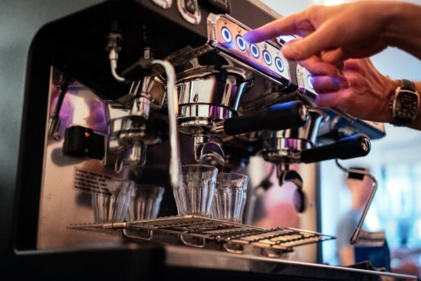 Person bruger espressomaskine på café.