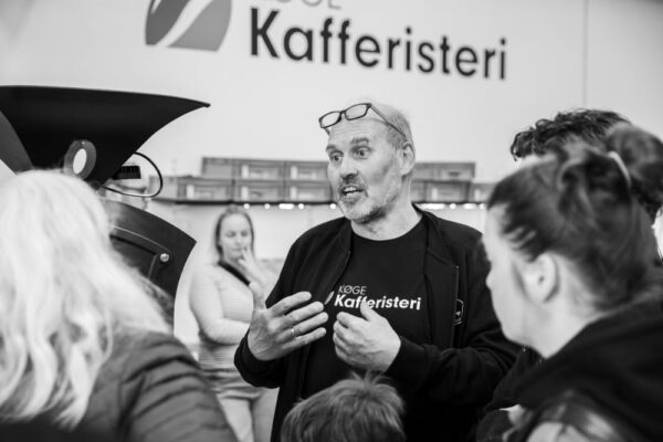 Mand taler til gruppe ved kafferi.