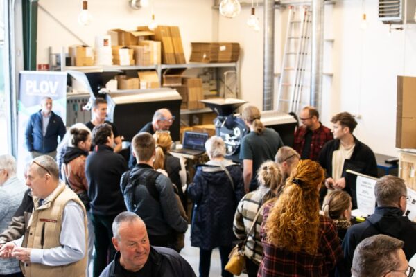 Folk samles ved kaffemaskine i butikslokale