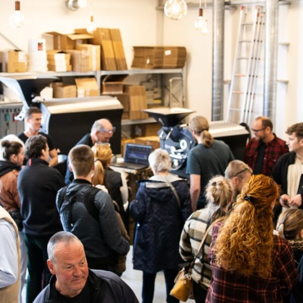 Folk samles ved kaffemaskine i butikslokale